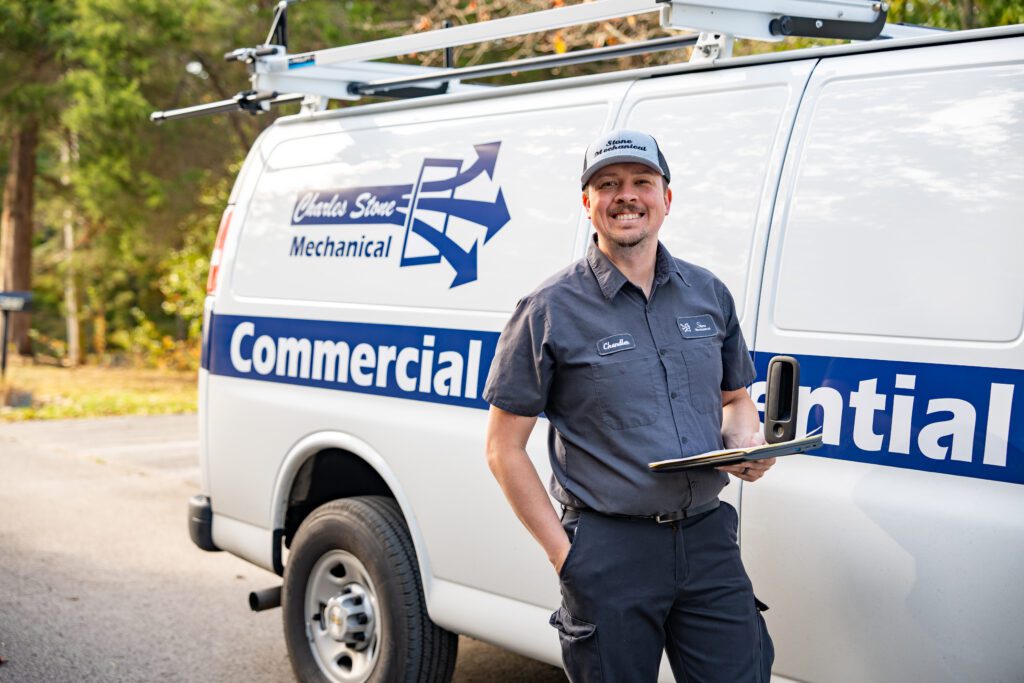 Smiling mechanical services technician in front of van