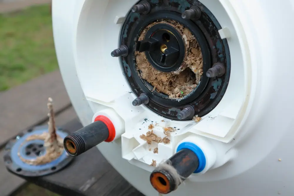 Taking out an electric heater from water heater to remove lime scale residue on it as part of a maintenance.