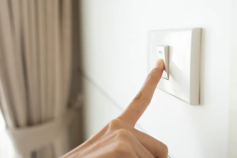 close up hand of woman turning on or off light switch in a home.