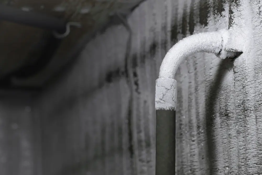 Frozen plumbing with a thick layer of white frost in the chilly cold winter. The frozen water pipe froze in the harsh winter at low temperatures.